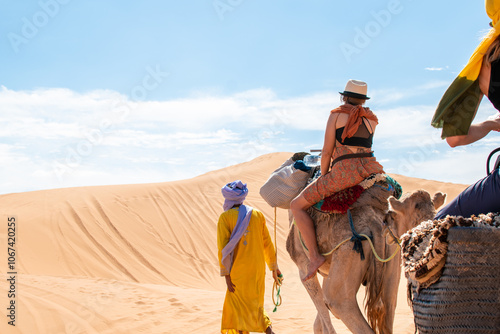 Turistas en el desierto del Sahara montando a camello con guía photo