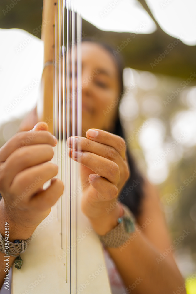 Woman musician delicately playing the strings of a harp in the park Woman musician delicately playing the strings of a harp in the park