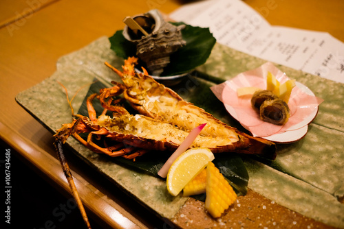 close up of Japanese grilled big king size prawns opened in two sides in half with lemon slice and shellfish at the back