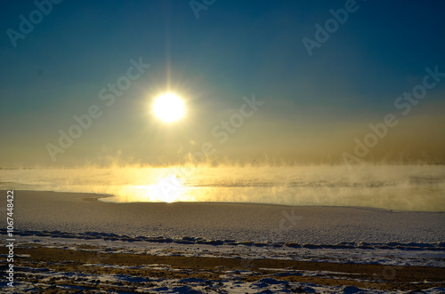 A delicate mist rises above the lake, like a magical haze created by the temperature shift. The sunset fills the horizon with a soft, warm glow. photo