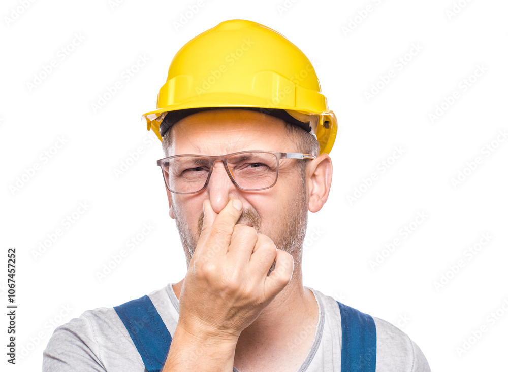 Dissatisfied construction worker holding his nose closed has disgusting expression on face, something stinky, isolated on white background. Craftsman against white wall Dissatisfied construction worker holding his nose closed has disgusting expression on face, something stinky, isolated on white background. Craftsman against white wall