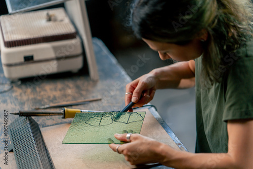 Photography in large green workshop, a thin woman with green hair at a large table cuts out