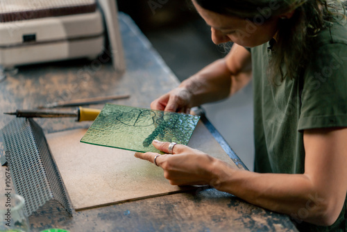 Photography in large green workshop, a thin woman with green hair at a large table cuts out