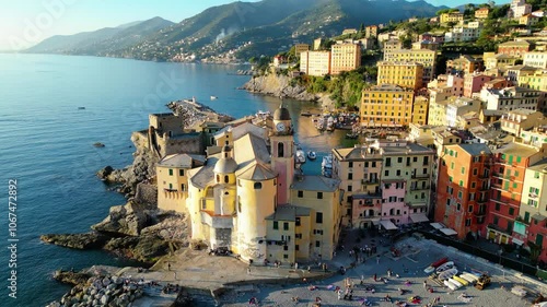 Camogli, a charming fishing village on Italy's Ligurian coast, captured from the air at sunset, reveals its colorful houses and historic harbor bathed in a warm, golden light photo