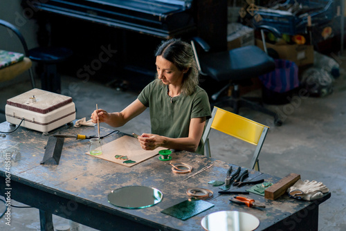 in a large green workshop on a woman with green hair creates decorative flowers working with metal tape decor on the mirror handicrafts photo