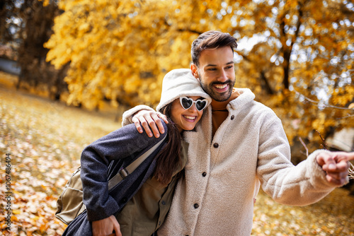 Young happy couple hugging and walking in the park. Colorful park on sunny autumn day.