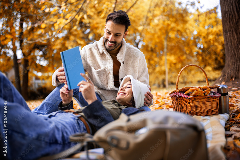 Young cute couple has picnic and reads book together in an colorful autumn park. Young cute couple has picnic and reads book together in an colorful autumn park.