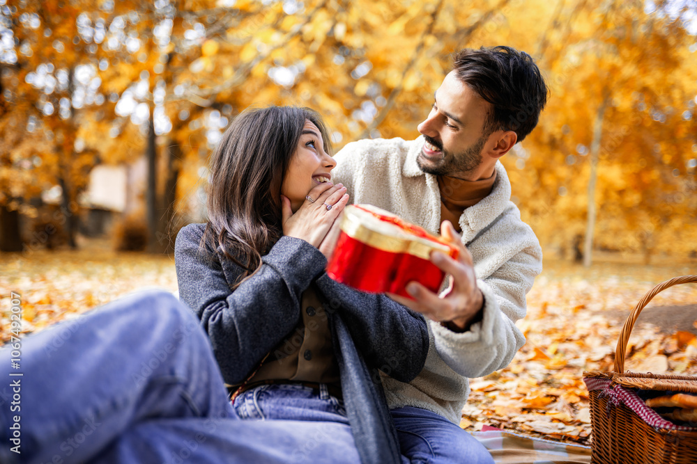 Boyfriend surprises his girlfriend on Valentines day with a gift on a picnic. Boyfriend surprises his girlfriend on Valentines day with a gift on a picnic.