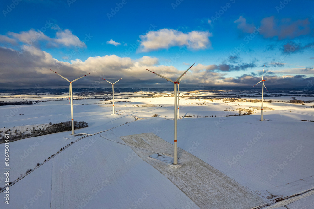 Drone shot of wind turbines in late afternoon light in flat snowy northern German landscape
