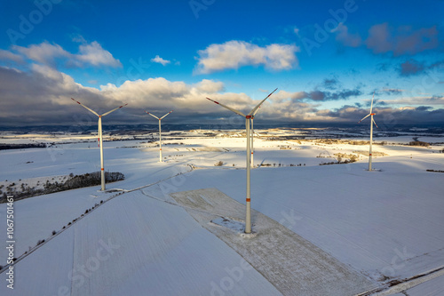 Obraz na płótnie Drone shot of wind turbines in late afternoon light in flat snowy northern German landscape w salonie