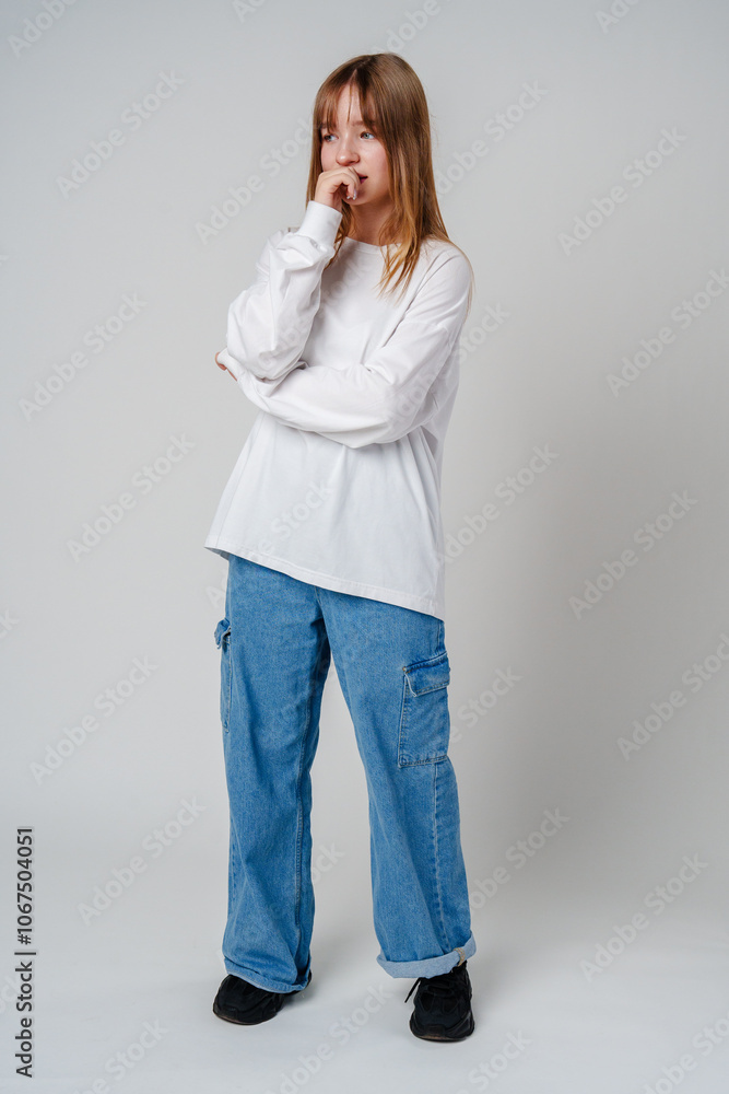 A young girl in a white sweatshirt shows a thoughtful expression against a plain background A young girl in a white sweatshirt shows a thoughtful expression against a plain background