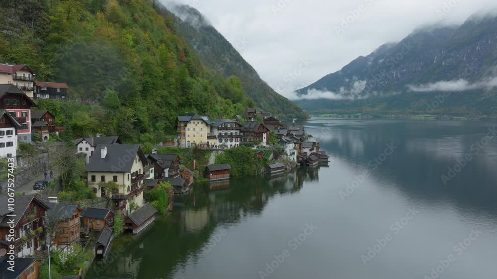 Aerial views capture Hallstatt, Austria, where clouds mirror in the calm lake waters. The tranquil landscape showcases the charming village nestled in the Alps Aerial views capture Hallstatt, Austria, where clouds mirror in the calm lake waters. The tranquil landscape showcases the charming village nestled in the Alps