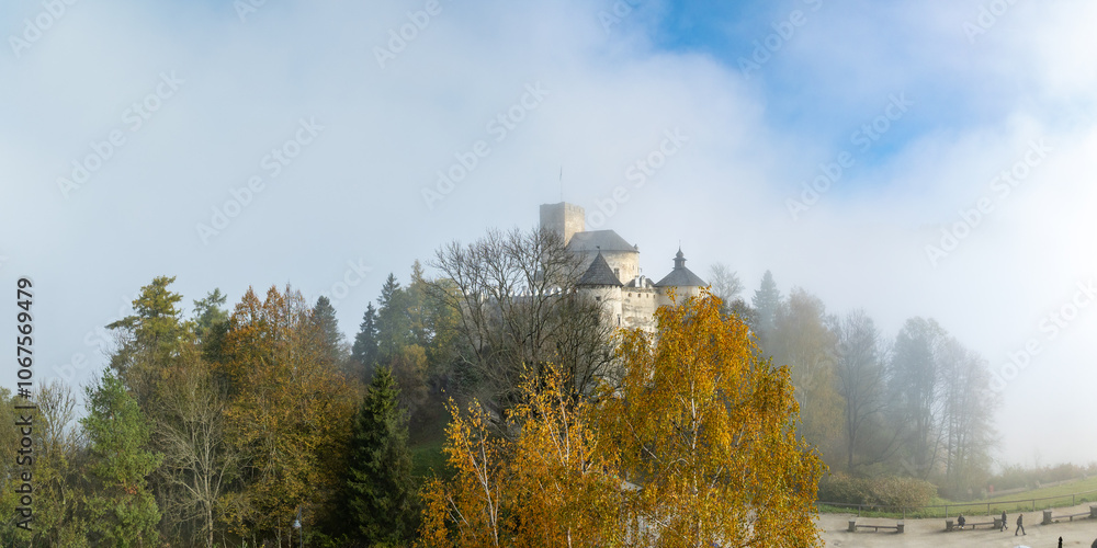 Poland. Medieval castle in Niedzica, dating to 14th century (upper castle) in autumn in October and morning fog. Trees in beautiful fall colors. Sunrise light. Aerial drone panorama