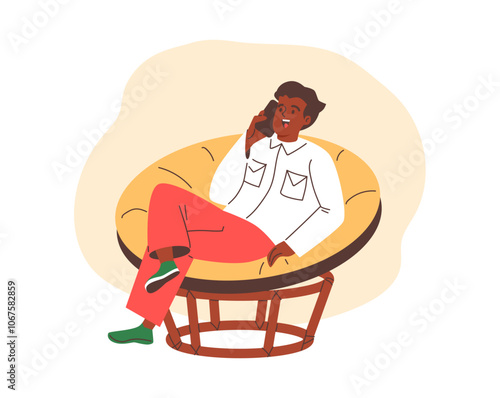 Man sits in a soft chair and talks on the phone.