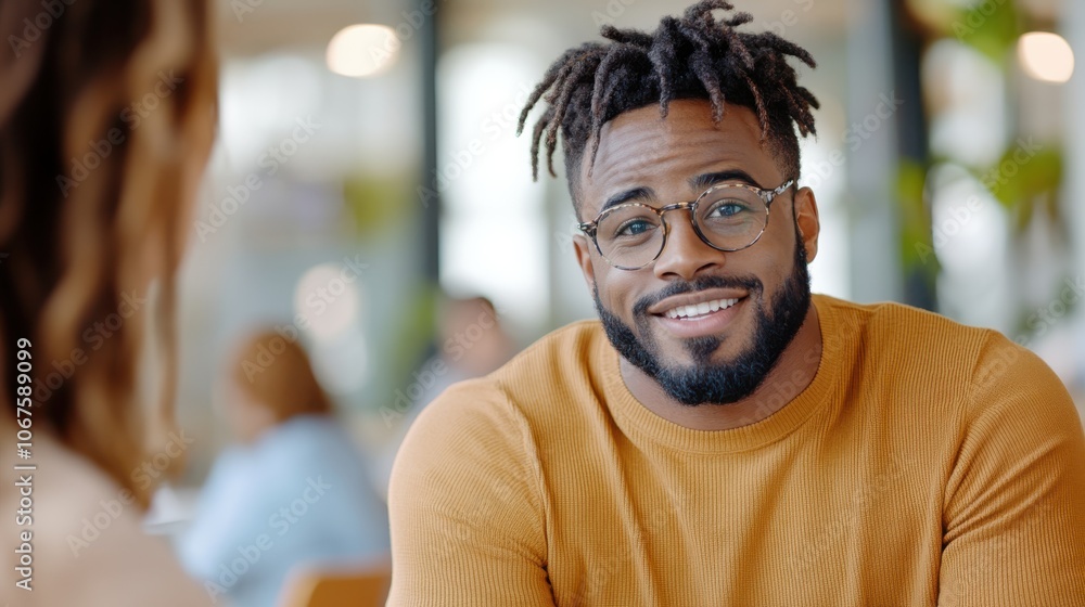 A cheerful man with styled hair and glasses engages in a friendly conversation indoors, showcasing approachability and warmth, creating a welcoming atmosphere. A cheerful man with styled hair and glasses engages in a friendly conversation indoors, showcasing approachability and warmth, creating a welcoming atmosphere.