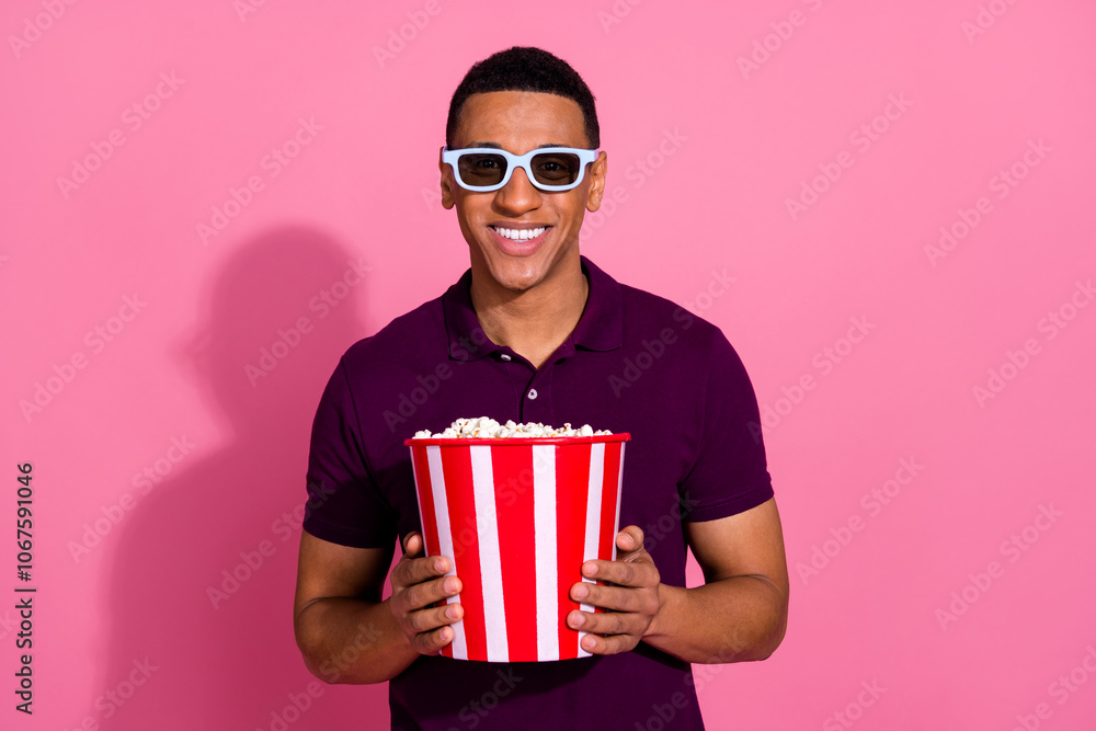 Photo portrait of attractive young man watch 3d movie eat popcorn dressed stylish violet clothes isolated on pink color background Photo portrait of attractive young man watch 3d movie eat popcorn dressed stylish violet clothes isolated on pink color background