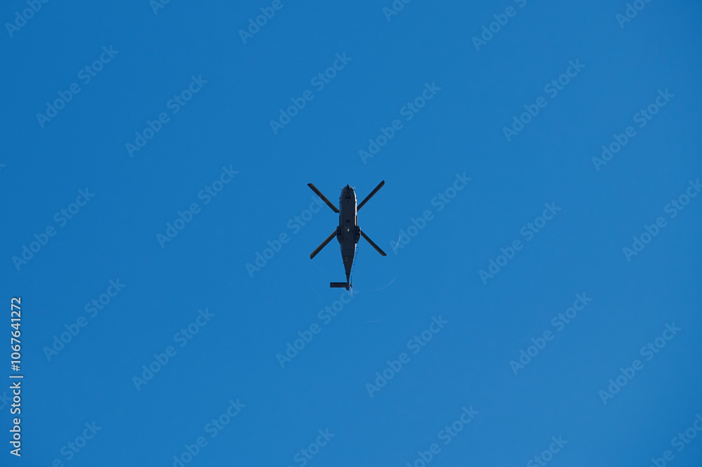 Silhouette of a helicopter flying against a clear blue sky Silhouette of a helicopter flying against a clear blue sky