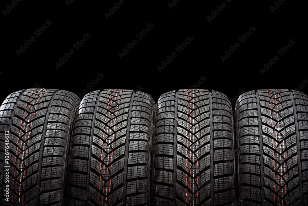 Fototapeta premium Four winter tires standing on black background