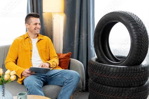 Slika na platnu Mechanic browsing online tire shop on tablet with tires in background