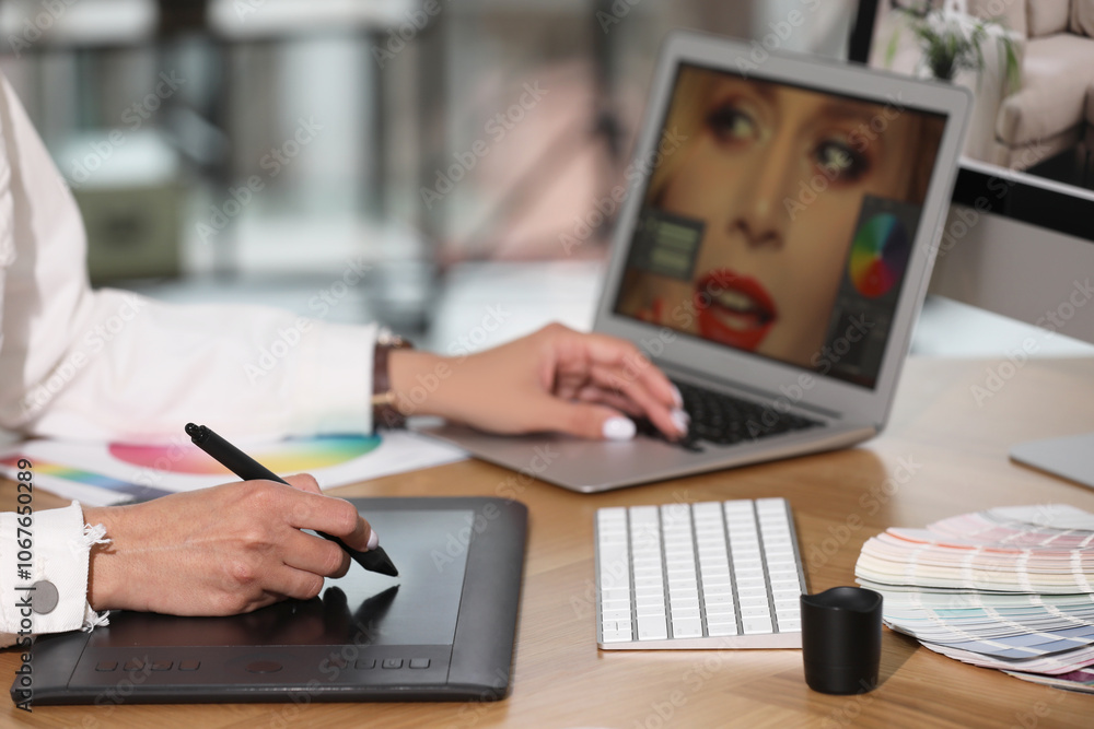 Professional retoucher working on graphic tablet and laptop at table, closeup Professional retoucher working on graphic tablet and laptop at table, closeup