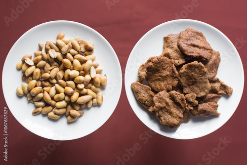 Overhead view of kuli-kuli and roasted peanuts on a white plate, top view of nigerian groundnut cakes and groundnuts on a plate