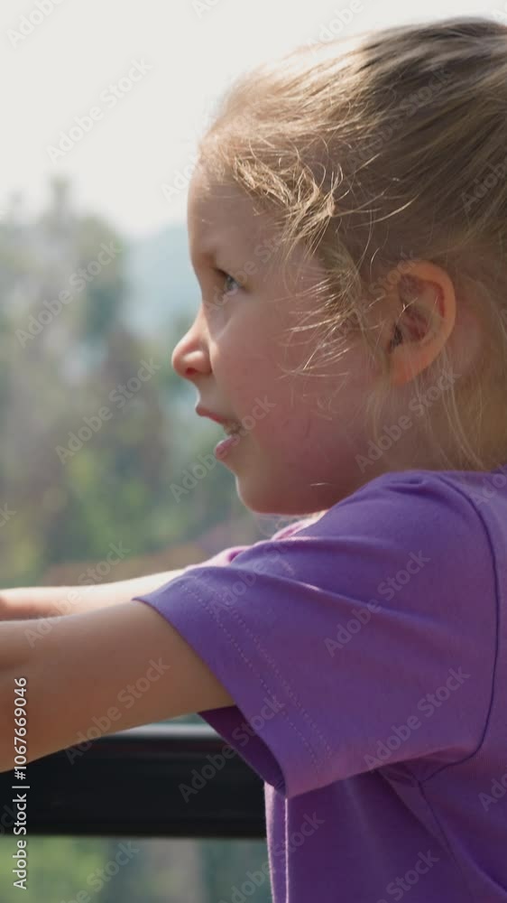 Confused little girl with braid leans on chair back looking at mountains from cabin with window of ropeway close side view slow motion Confused little girl with braid leans on chair back looking at mountains from cabin with window of ropeway close side view slow motion