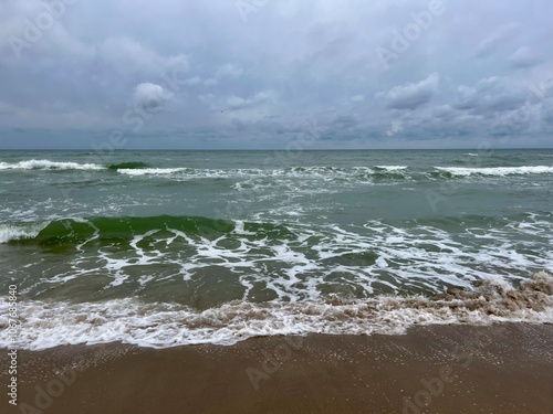 cloudy grey seascape, waved sea horizon, windy at the sea, empty beach