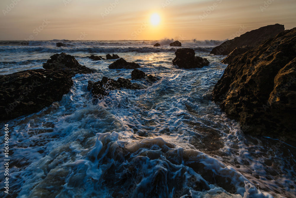 coastal sunset scene, waves rush in from the open sea, filling the space between the dark, rugged rocks coastal sunset scene, waves rush in from the open sea, filling the space between the dark, rugged rocks