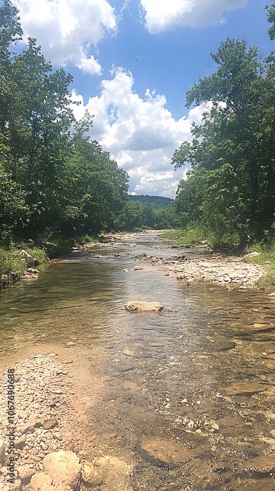Fototapeta premium A serene river scene surrounded by lush greenery and blue skies.