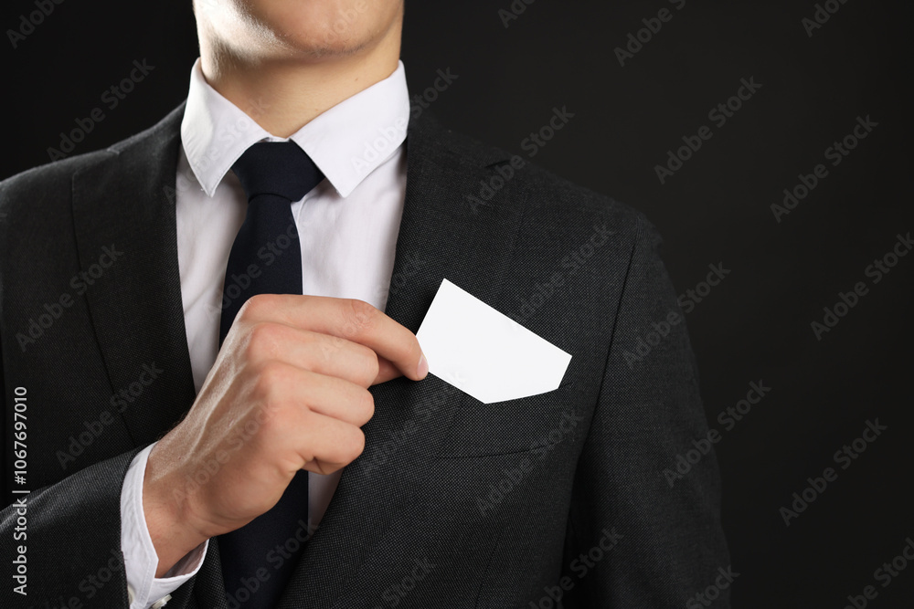 Man taking blank business card from pocket of his jacket on black background, closeup. Mockup for design Man taking blank business card from pocket of his jacket on black background, closeup. Mockup for design