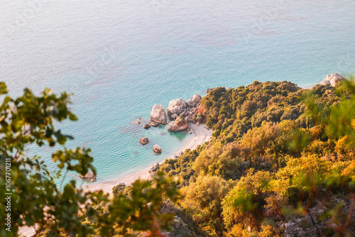 bird's eye view from a hiking trail leading to the deserted and inaccessible Krorez beach in southern Albania, a beach with turquoise blue clear water, white pebbles and rocks jutting into the sea