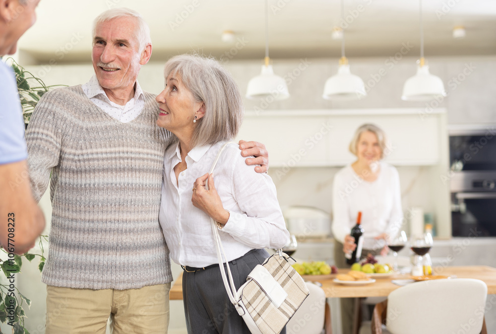Obraz premium Two elderly couples meet for a holiday dinner at home. Greet each other