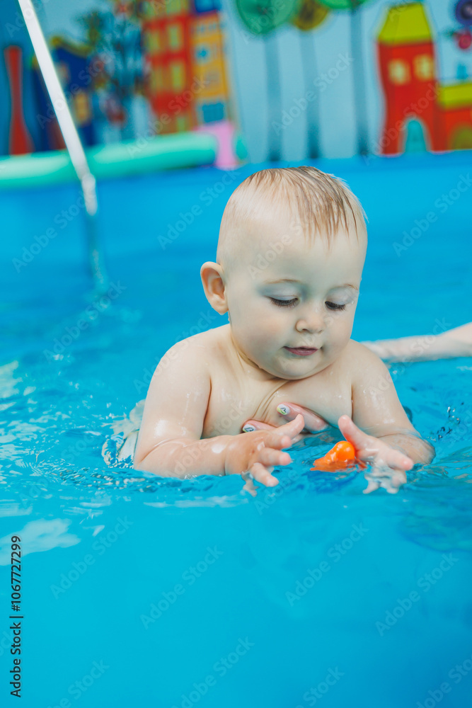 A 1-year-old boy learns to swim in a children's pool with a coach. Swimming courses for children. Children's pool. A 1-year-old boy learns to swim in a children's pool with a coach. Swimming courses for children. Children's pool.