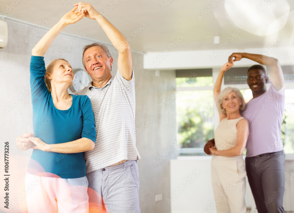 Obraz premium Happy smiling elderly woman enjoying impassioned merengue with male partner in latin dance class. Social dancing concept