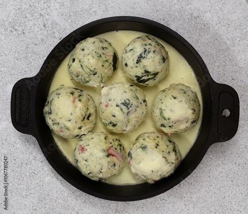 Italian pasta. Closeup view of ricotta, spinach and cheese malfatti with a creamy sauce in a black rustic dish on the table	
 photo