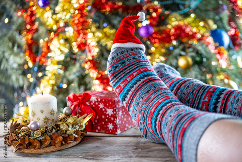 pair feet wearing colorful Christmas socks, resting near decorated Christmas tree, cozy winter scene, warm and inviting atmosphere, holiday spirit photo