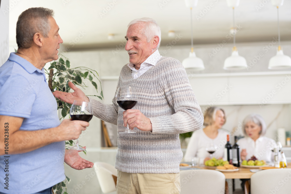 Elderly men drink red wine and tell each other news during a festive dinner at home Elderly men drink red wine and tell each other news during a festive dinner at home