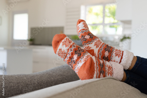 Christmas time, Relaxing at home, asian woman wearing cozy festive socks on sofa