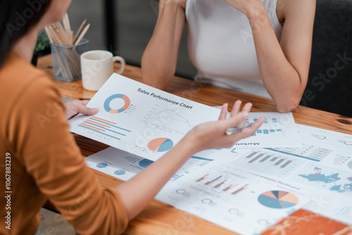 Two professionals discussing sales performance charts in a modern office environment, focusing on data analysis and strategy.