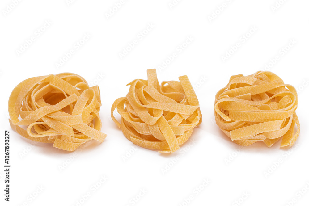 Three Classic Italian Raw Egg Fettuccine - Isolated on White Background. Dry Twisted Uncooked Pasta. Italian Culture and Cuisine. Raw Golden Macaroni Pattern - Isolation Three Classic Italian Raw Egg Fettuccine - Isolated on White Background. Dry Twisted Uncooked Pasta. Italian Culture and Cuisine. Raw Golden Macaroni Pattern - Isolation