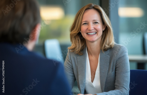 professional woman in her late thirties smiling during meeting, exuding confidence and warmth. Her engaging demeanor creates positive atmosphere for collaboration