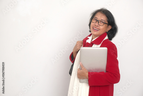 Asian woman wearing red suit and holding a laptop, going home from work to celebrate Christmas photo