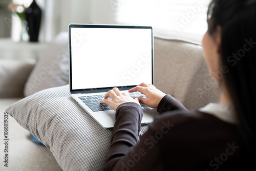 Woman using and typing on laptop with blank white screen. Mockup blank white desktop screen