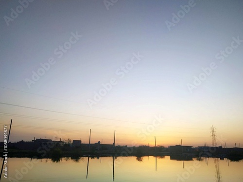 Tranquil Sunset Reflection Over Calm Waters in Rural Landscape