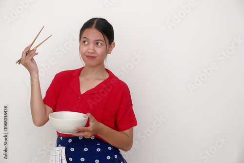 Indonesian woman standing alone, holding white bowl and chopsticks in her hands photo