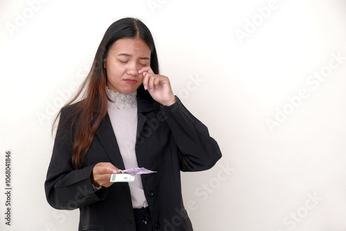 Indonesian businesswoman holding some small cash Rupiah money with unhappy looking facial expression photo