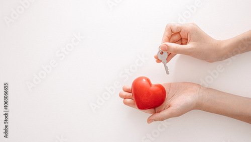 Foto Two hands are positioned with a small key above a vibrant red heart, representing the idea of unlocking love and emotional security in a creative and artistic way