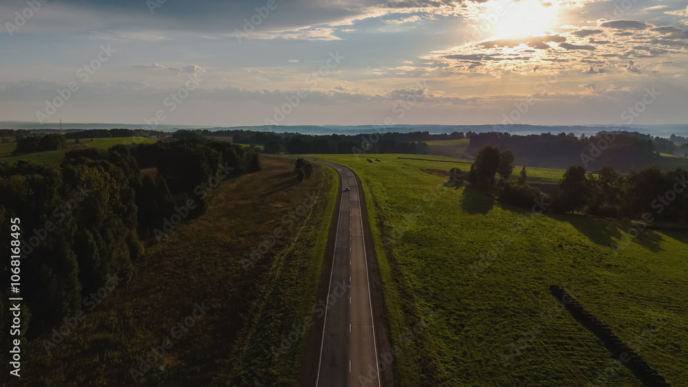 Fototapeta premium dawn over the road on which the car is traveling