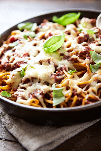 Baked spaghetti pasta with mozzarella cheese. Wooden background. Close up.