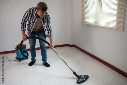 Man Vacuuming Floor in Bright, Minimalist Room with Blinds photo